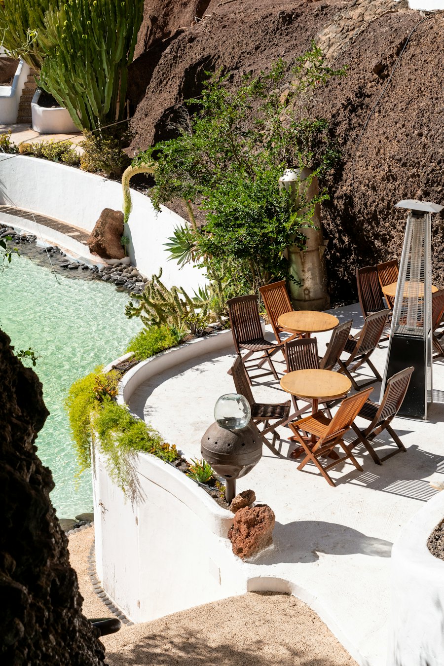 Patio con mesa y sillas junto a una piscina